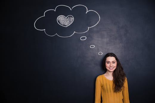 Beautiful happy young woman thinking about love and standing with blackboard behind her-1